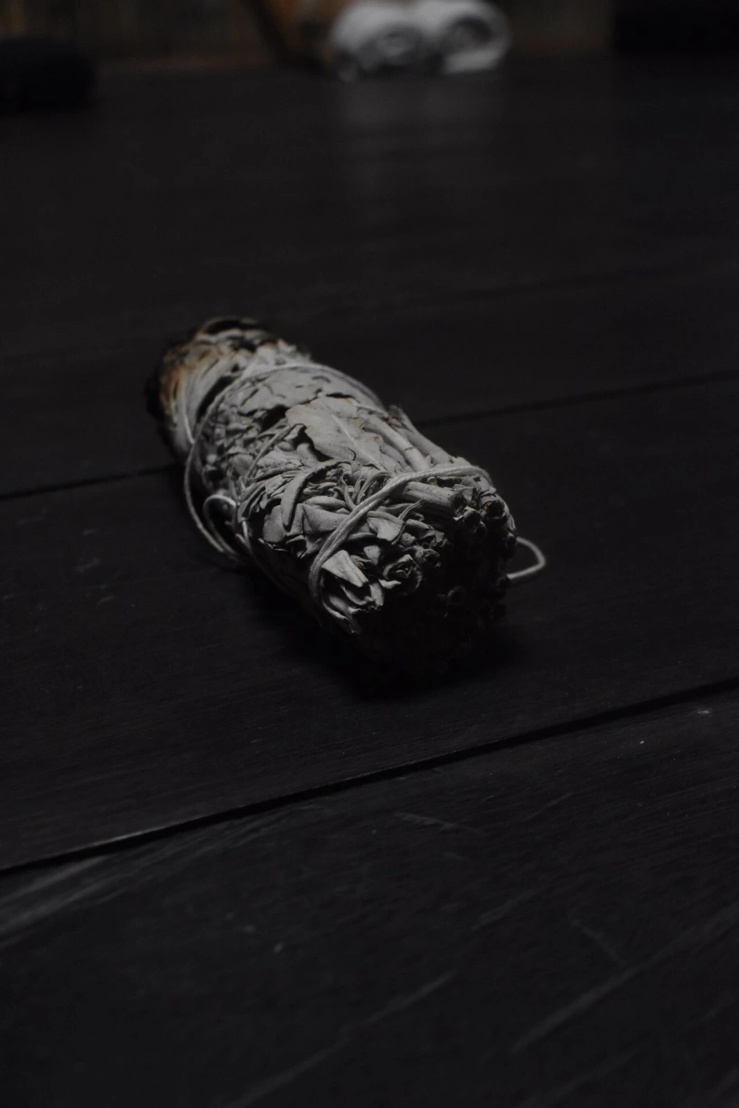 A white sage bundle resting on dark wood
