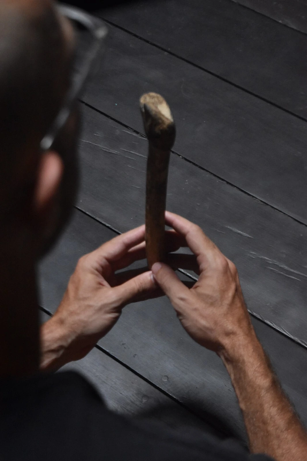 Hands holding a sacred talking stick against dark weathered wood